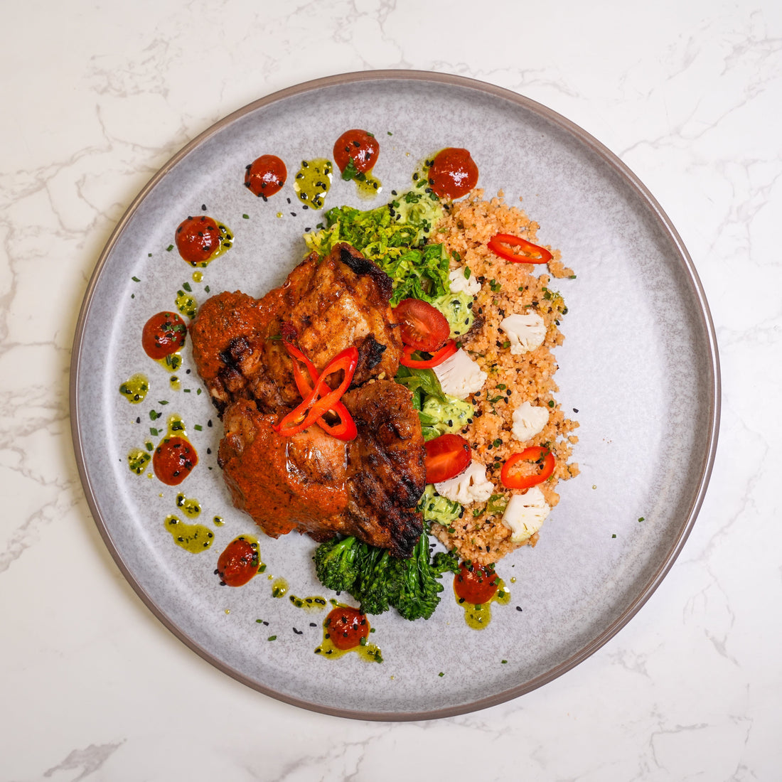 High protein grilled chicken meal prep for Doctors with couscous, broccoli, cauliflower and spicy sauce served on a plate