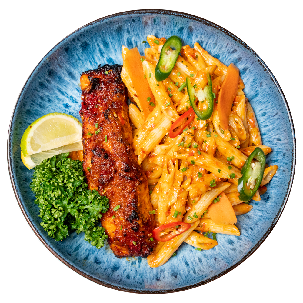 Fresh high-protein fish and pastat meal with garnishes served on a blue plate for affordable meal delivery UK.