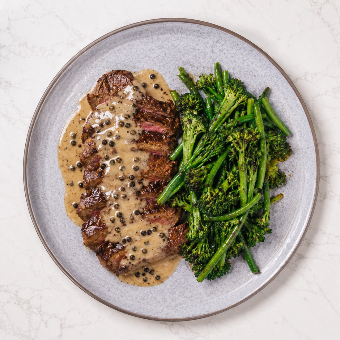 Grilled rump steak with peppercorn sauce and tenderstem broccoli served as a high protein meal prep dish for lorry drivers.